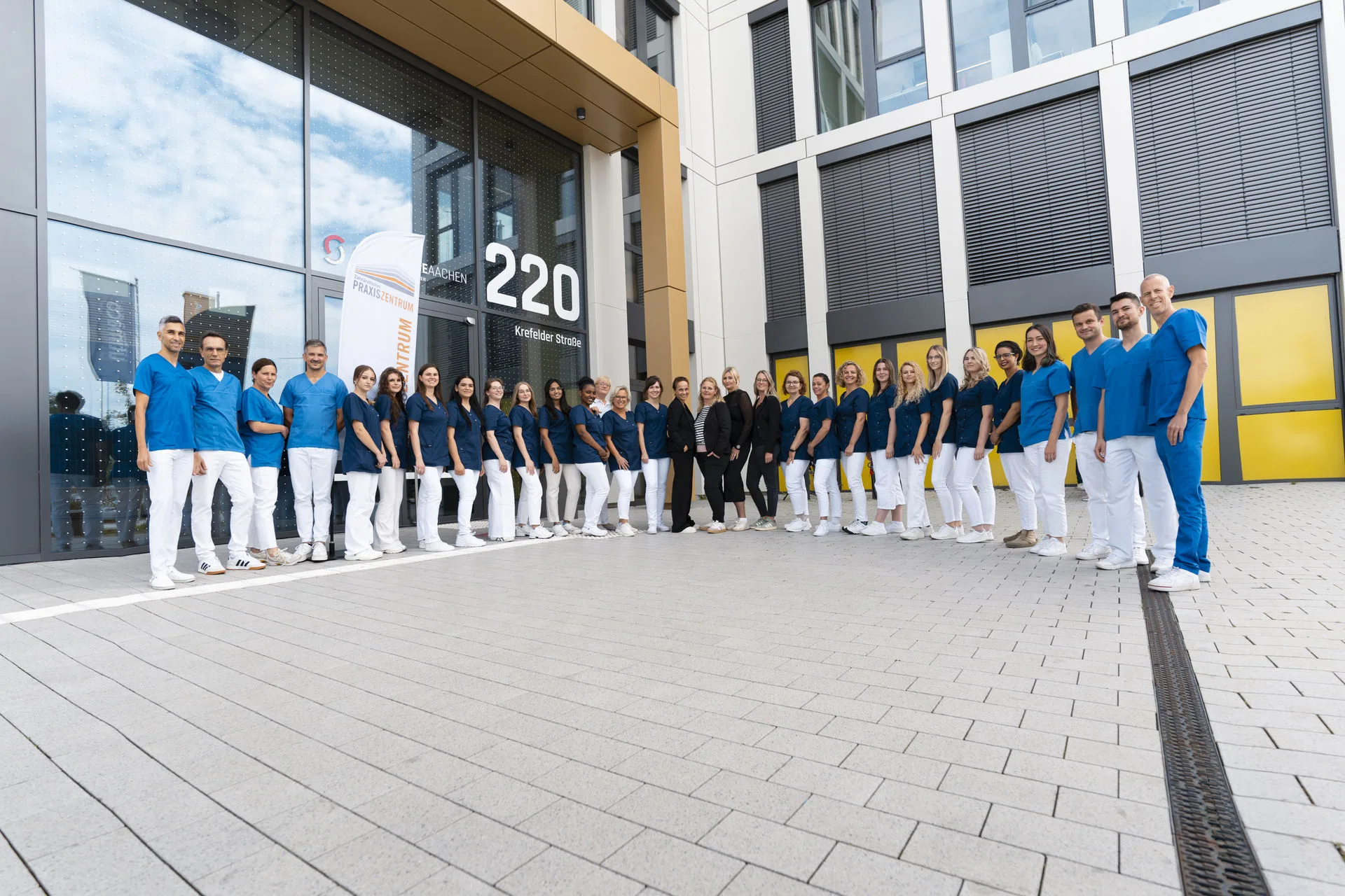 Das gesamte Team des Zahnärztlichen Praxiszentrums Aachen vor dem Praxisgebäude